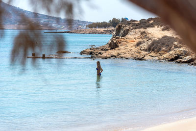 Full length of shirtless man in sea against sky