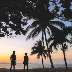 Silhouette people on beach against sky during sunset