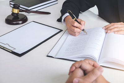 Cropped image of lawyer writing in book with person at courthouse