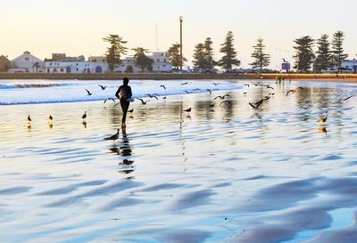 Reflection of person in lake against sky during winter