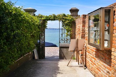 Walkway by wall and plants against sky