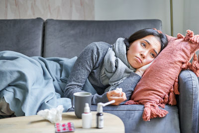 Portrait of young woman sitting on sofa at home