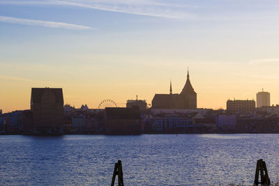 River by city against sky during sunset