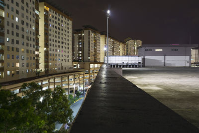 Illuminated street amidst buildings in city at night