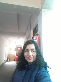 Portrait of smiling woman standing in corridor