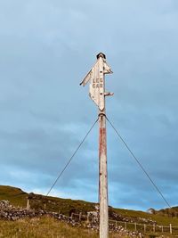 Low angle view of bird perching on wooden post against sky