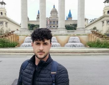 Portrait of young man against building in city