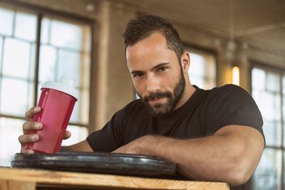 Portrait of handsome bearded man with drink bottle on table