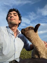 Young man with sheep against sky