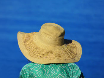 Rear view of woman wearing sun hat against blue sea on sunny day