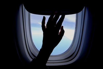 Cropped hand of woman touching airplane window