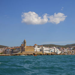 Buildings by sea against sky