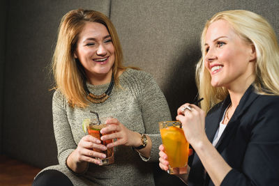 Delighted women enjoying cocktails in pub