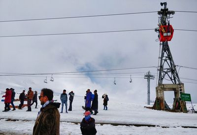 People on snow covered landscape against cloudy sky