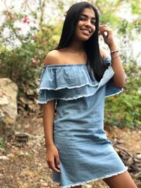 Portrait of smiling young woman standing against trees