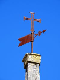 Low angle view of weather vane against blue sky