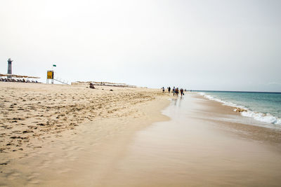 People on beach against clear sky