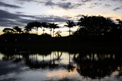 Silhouette trees by lake against sky during sunset