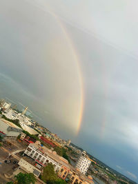 Rainbow over buildings in city against sky