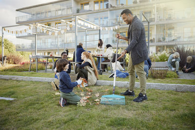 Neighbors relaxing and raking leaves in communal outdoor area