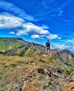 Rear view of man standing on mountain against sky