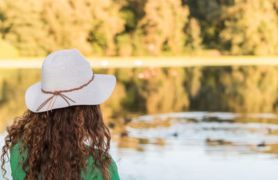 Rear view of woman wearing hat by lake