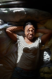 Midsection of smiling young woman relaxing on bed at home