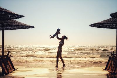 People standing on beach against clear sky