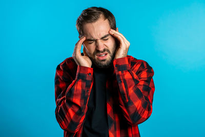 Portrait of young man standing against blue background