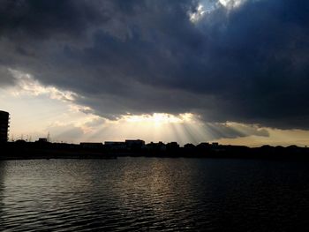 Scenic view of river against cloudy sky at sunset