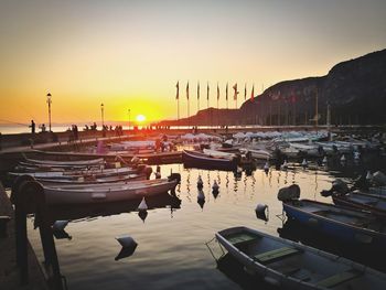 Boats moored at harbor during sunset
