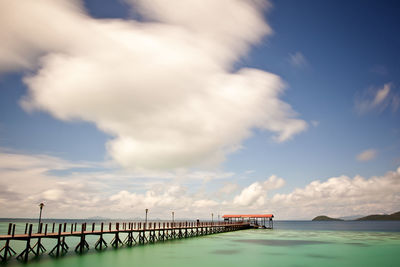 Pier on sea against cloudy sky