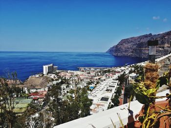 High angle view of townscape by sea against clear blue sky