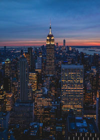 Illuminated buildings in city against sky during sunset