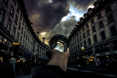 Close-up of person holding crystal ball in city 