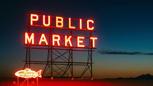 Low angle view of illuminated text against sky at night