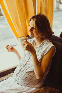 Young woman using mobile phone while sitting on seat