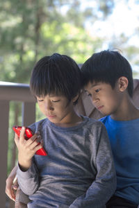 Brothers using mobile phone in porch