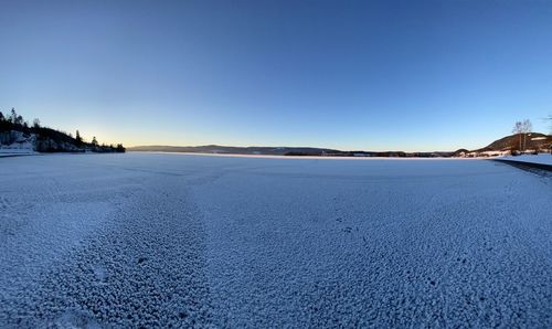 Scenic view of snow covered land against clear blue sky