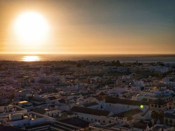 High angle view of townscape by sea against sky during sunset