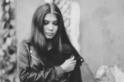 Portrait of young woman standing against wall