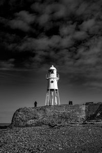 Lighthouse by sea against sky