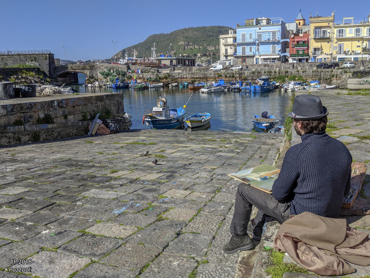 REAR VIEW OF MEN SITTING ON BOAT MOORED AT HARBOR