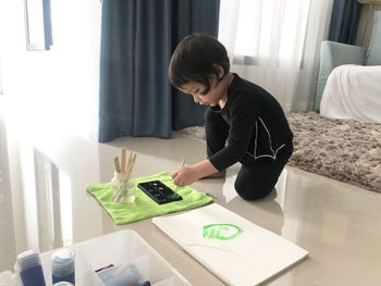 Boy painting in book on floor at home