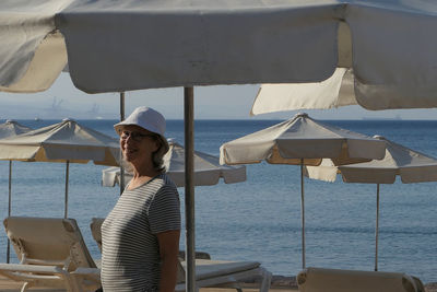 Senior woman standing and smiling on the beach 