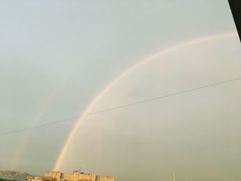 Low angle view of rainbow over building against sky