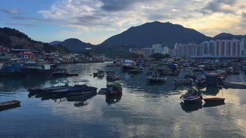 Boats moored in harbor by town against sky