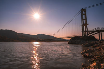 Bridge over river against sky during sunset