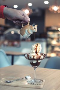 Cropped hand pouring sauce on dessert in restaurant