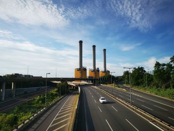 Road by factory against sky